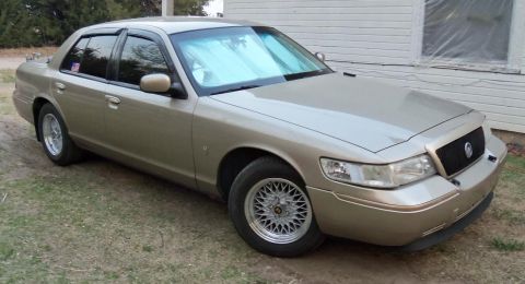 2000 Mercury Grand Marquis - This 2000 Mercury Grand Marquis sedan is parked on a grassy area next to a building.