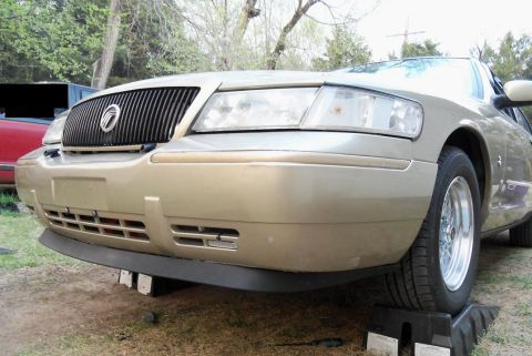 2000 Mercury Grand Marquis - A gold Mercury Grand Marquis is shown from a low front 3/4 angle, with its front end elevated on ramps.