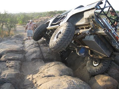 1986 Ford Bronco - An off-road vehicle is stuck on a rocky terrain, with two people observing.