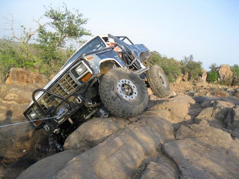 1986 Ford Bronco - This heavily modified SUV is navigating a challenging rocky terrain, its off-road capabilities.