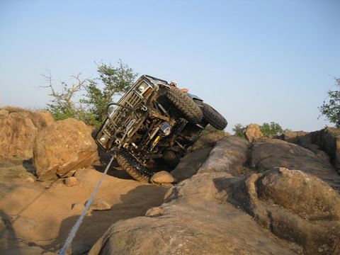 1986 Ford Bronco - Off-road vehicle attempts to climb a difficult rocky terrain, using a tow rope for assistance.