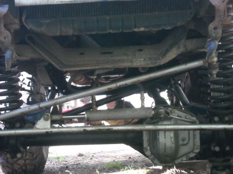1979 Ford F-150 - The underside of a vehicle shows extensive modifications to the suspension and steering systems.