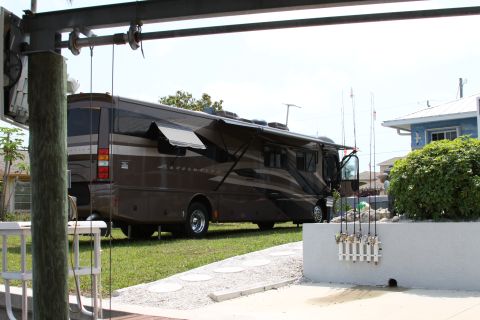 2003 Ford F-350 - This motorhome is parked on a grassy area with fishing rods visible in the foreground.
