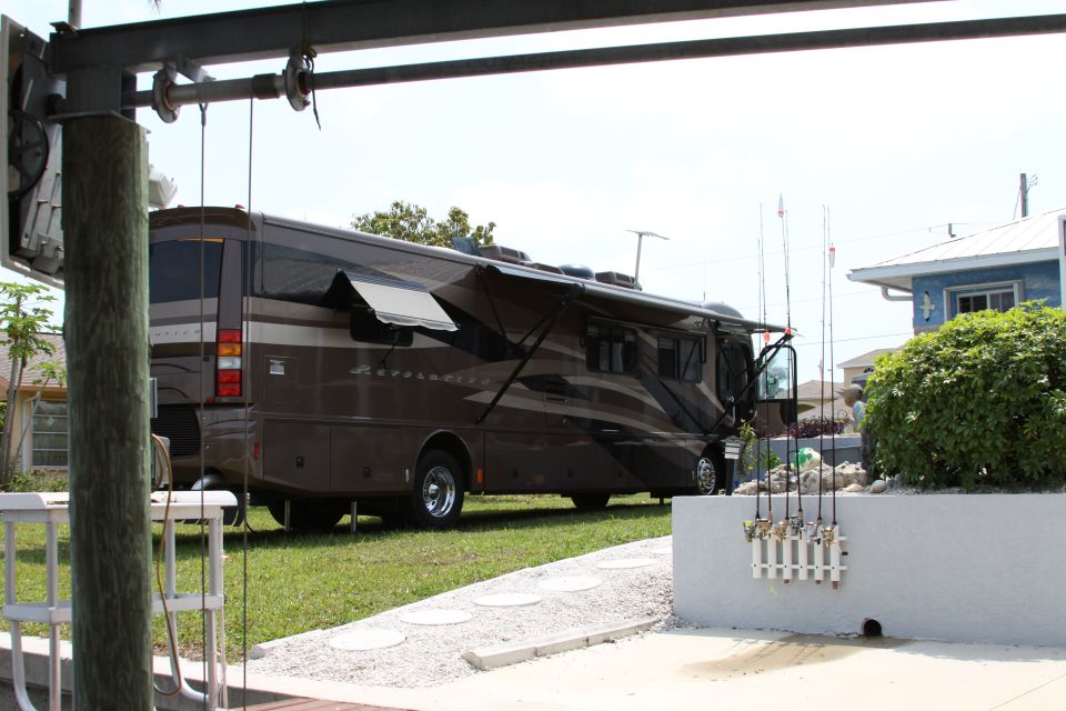 Brown motorhome with awnings extended, parked on grass