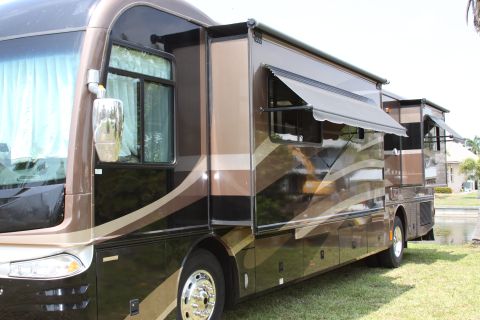 2003 Ford F-350 - Two motorhomes parked on grass, one with its awnings and slide-outs deployed.