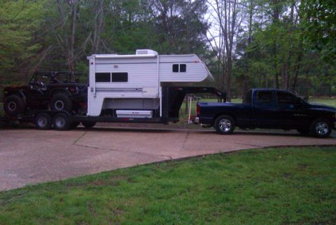 1967 Ford Mustang - A dark pickup truck tows a trailer carrying a camper and an off-road vehicle.