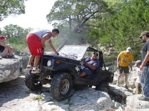 1973 Ford Bronco - Off-road vehicle with people assisting it on a rocky trail.