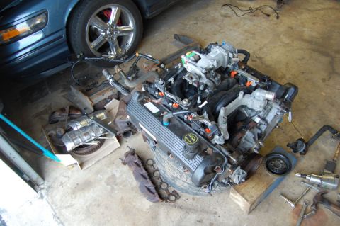 1985 Mercury Grand Marquis - Engine components are laid out on the floor, with a car's wheel visible in the background.