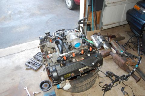 1985 Mercury Grand Marquis - Engine assembly with various engine parts and tools scattered around it.