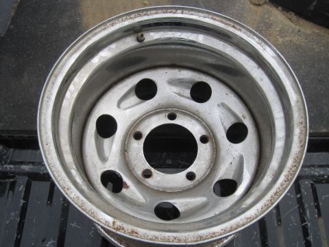 1979 Ford Bronco - Close-up of a silver steel wheel, likely from a truck or SUV, showing signs of wear and rust on the rim.