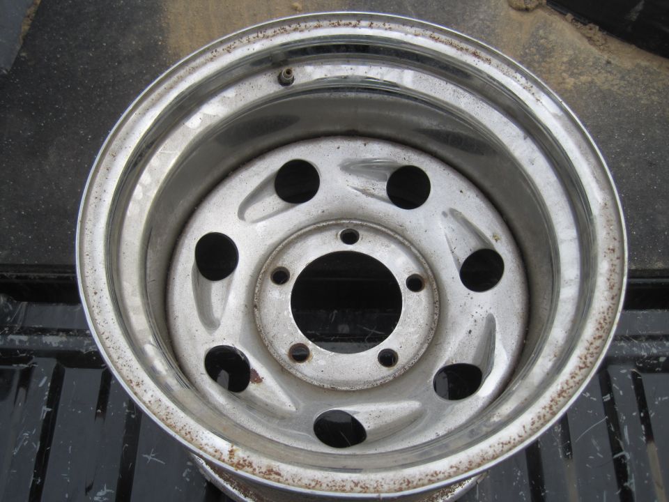 Silver steel wheel with six lug holes and a rusty rim