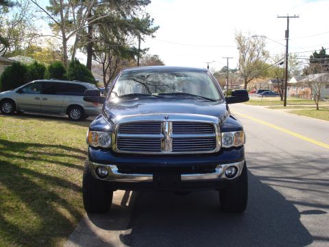 2005 Dodge 2500 - A blue Dodge Ram pickup truck is parked on the street in front of a house. A silver minivan is parked in the yard.