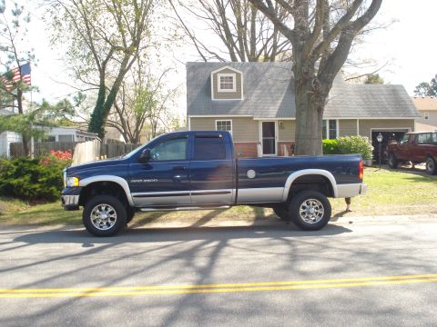 2005 Dodge 2500 - A blue Dodge Ram 2500 pickup truck is parked on the side of a residential street.