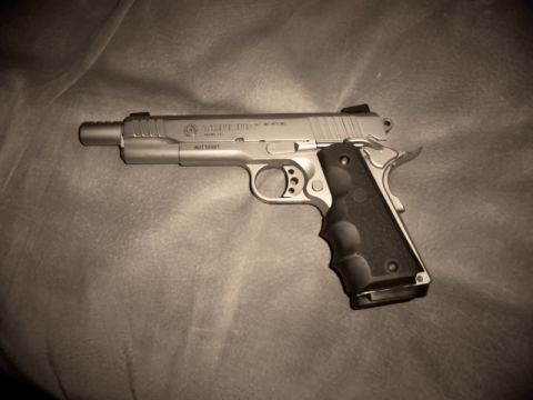 2000 Mercury Grand Marquis - A close-up of a Taurus 1911 pistol, showing its metallic finish and checkered grips.