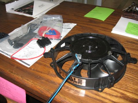 1995 Ford Bronco - A black electric radiator/cooling fan branded 'DERALE' rests on a wood table, with an installation kit including red wiring, blue crimp con…