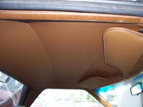 1972 Ford Ranchero - The interior of a vehicle shows a brown headliner and a sun visor, with a partial view of the windshield and side window.