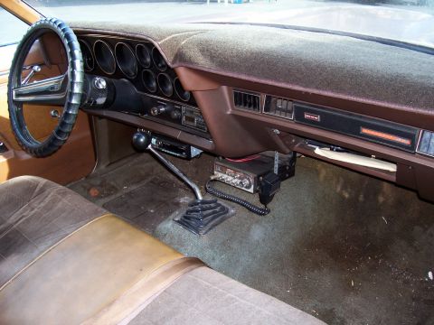 1972 Ford Ranchero - The interior of a 1972 Ford Ranchero features a brown dashboard, steering wheel, and seats, along with a CB radio mounted below the dash.