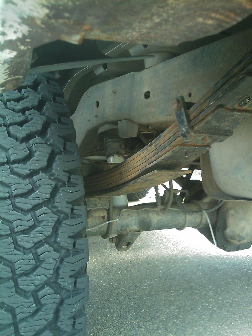 Rear leaf springs and axle assembly of a vehicle, with a tire visible on the left