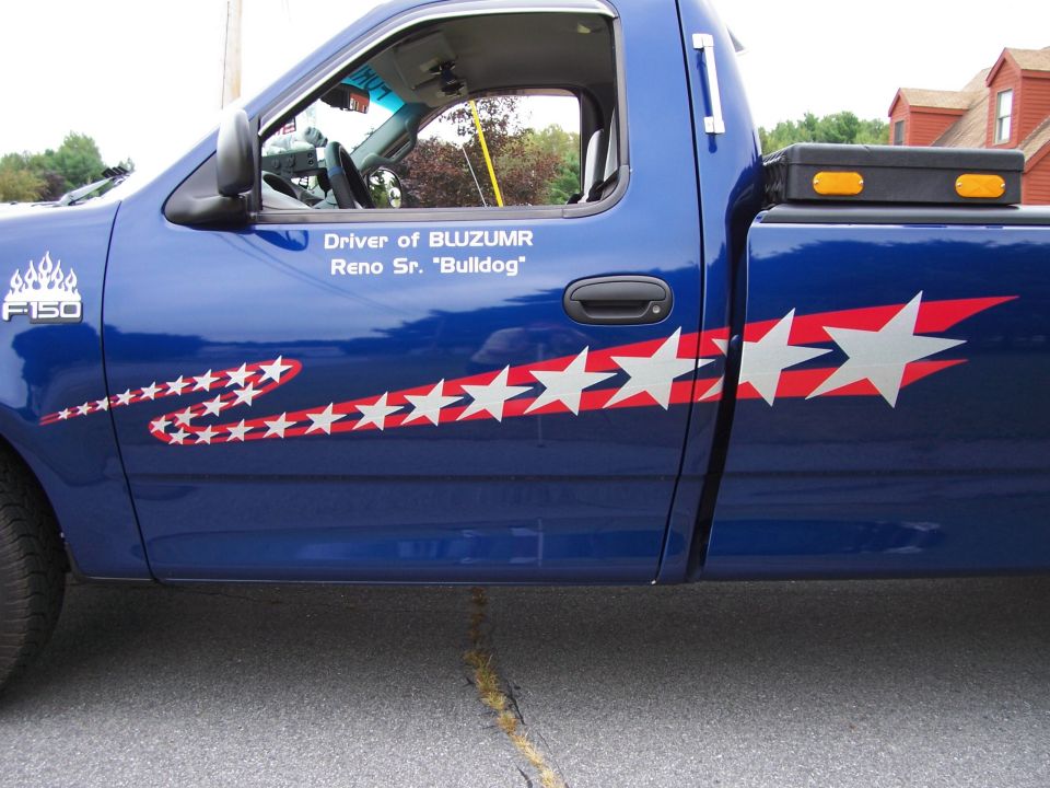 Side view of a blue 1998 Ford F-150 with star decals and "F-150" badge