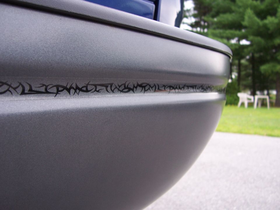 Close-up of a gray truck rear bumper with a black tribal graphic strip