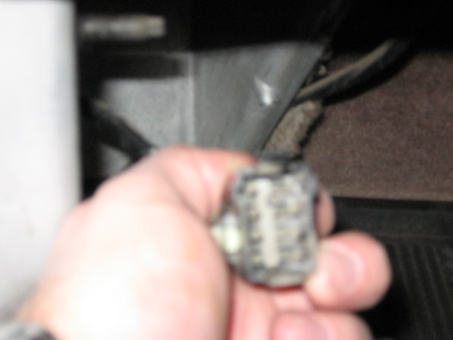 Hand holding a small electrical wiring connector inside a vehicle
