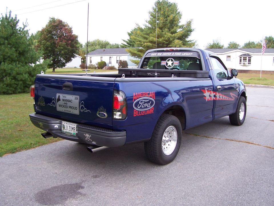 Dark blue Ford F-150 pickup, rear 3/4 view, with American Bluzumr star graphics and BLU-ZUMR Maine plate.