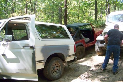 1989 Ford Bronco - A white 1987 Ford Bronco is parked in a wooded area with its driver's door open.