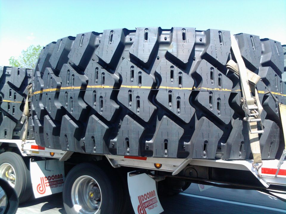 stack of huge tires on a flatbed trailer, strapped down