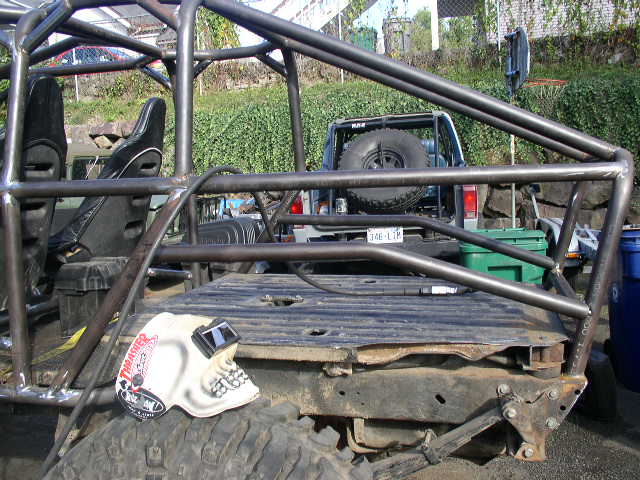 Bare-metal tube roll cage welded over the stripped rear floor of a 4x4