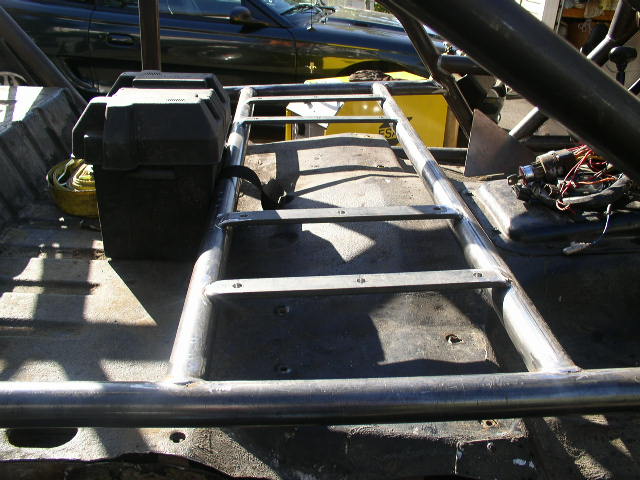 Stripped vehicle floor with welded steel tube frame, battery box and wiring harness