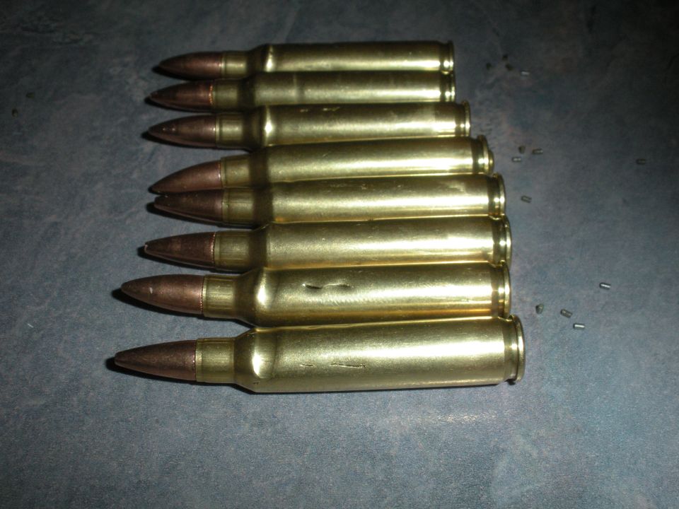 Several brass cartridges with copper-tipped projectiles laid out on a dark surface