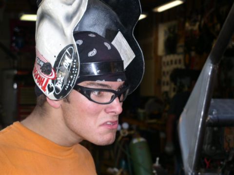 1979 Ford Bronco - A welder is seen wearing protective gear, including a helmet with a sticker and safety goggles, in a workshop setting.