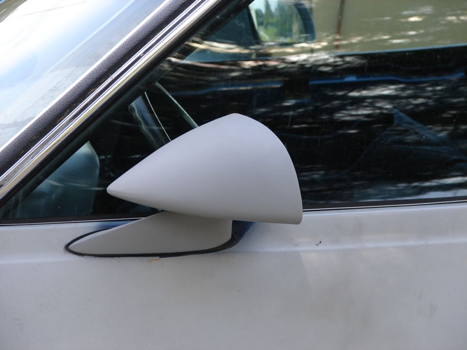 White car door with a gray side mirror and chrome trim around the window