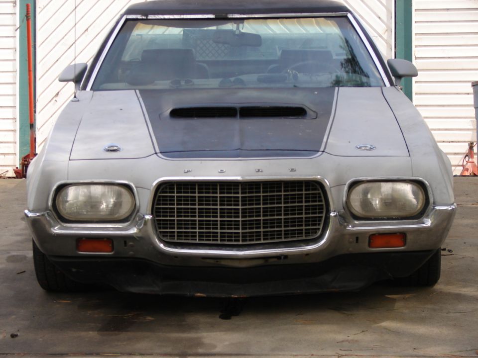 Front view of primer-gray 1970s Ford with egg-crate grille and hood scoop