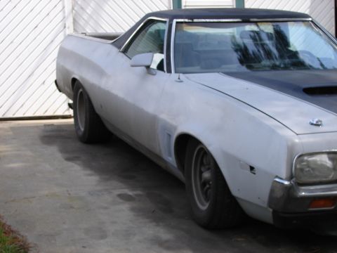 1973 Ford Ranchero - A light-colored Ford Ranchero with a black top is parked in front of a white garage door.