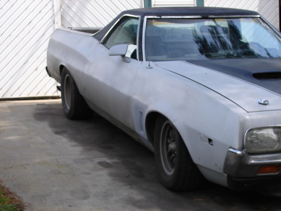 Light-colored Ford Ranchero with a black vinyl top, seen from the front-right quarter angle