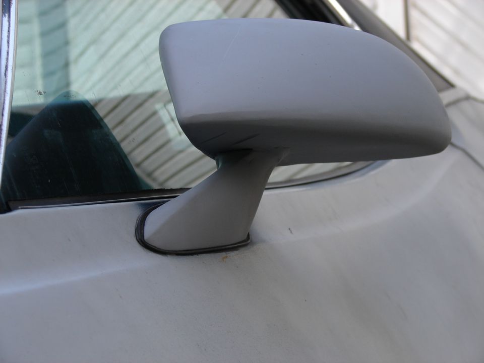 Car side mirror, appears to be unpainted or primed