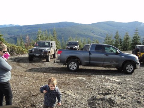 2005 Jeep Wrangler - Several off-road vehicles are parked on a dirt road in a mountainous, wooded area.