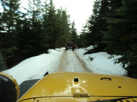 2005 Jeep Wrangler - Driving through a snowy forest road with another jeep ahead.