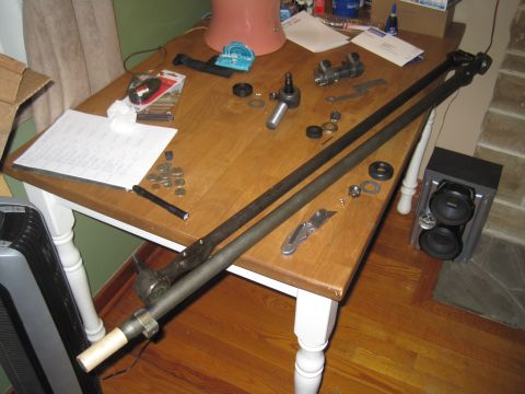 1979 Ford Bronco - Various steering linkage components are organized on a table, possibly for repair or assembly.