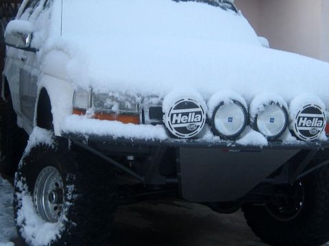 1996 Ford Bronco - A snow-covered SUV with auxiliary lights is parked outside.