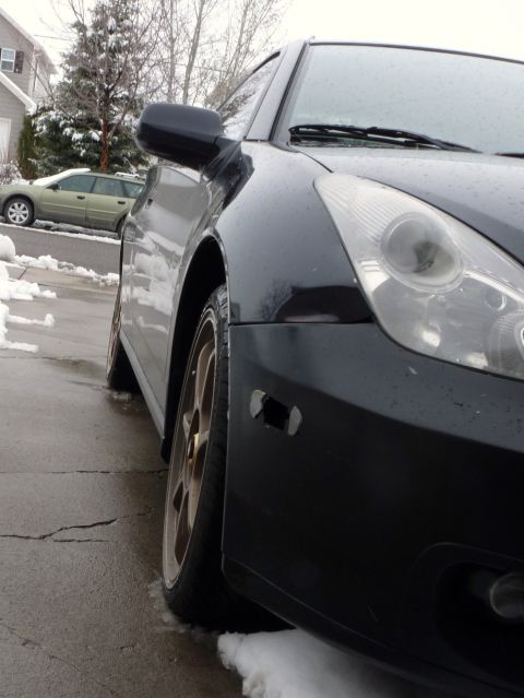 2006 Ford E350 - A black coupe with gold rims is parked on a wet driveway with snow on the ground.