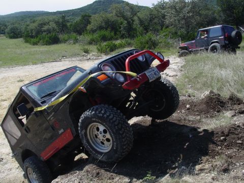 1973 Ford Bronco - Two Jeep Wranglers navigate a challenging off-road course on a sunny day.