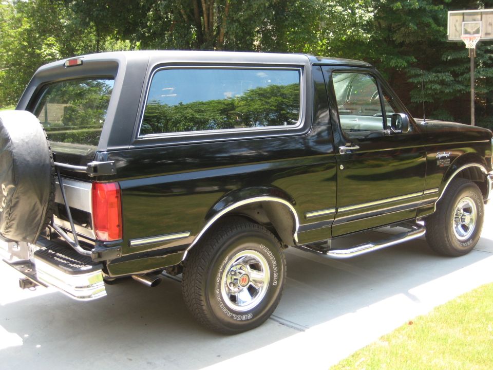 Black 1992 Ford Bronco parked on a driveway, side view with spare tire on the back