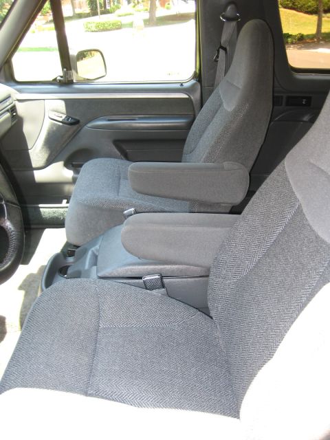 1992 Ford Bronco - The interior of the vehicle shows front seats with armrests and a view of the door panel.