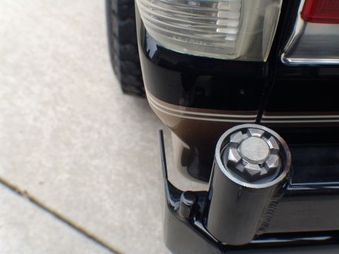 1996 Ford Bronco - Rear view of a black SUV showing a chrome tow hitch receiver and part of the taillight assembly.