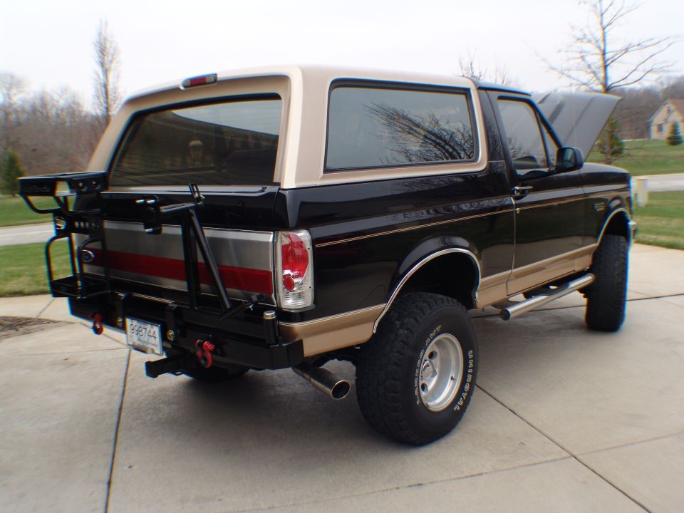 Black and tan Ford Bronco with a rear tire carrier and aftermarket bumper