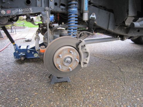 2008 Jeep Wrangler - Close-up of a modified Jeep Wrangler's front brake system, showing the rotor, caliper, and suspension components.