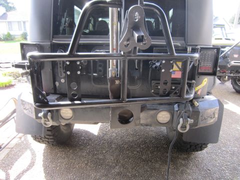 2008 Jeep Wrangler - Modified rear bumper and tire carrier assembly on a Jeep Wrangler, with another vehicle partially visible.