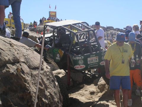 1979 Ford Bronco - A custom off-road buggy, number 122, tackles a challenging rocky course with onlookers present.
